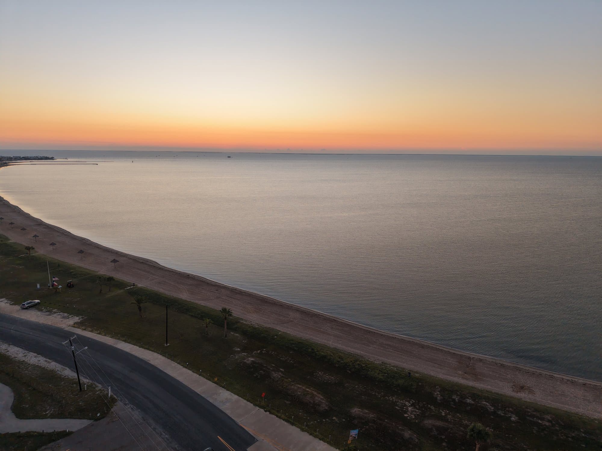 Serene coastal view featuring a sandy beach and calm sea under a glowing sunset sky.