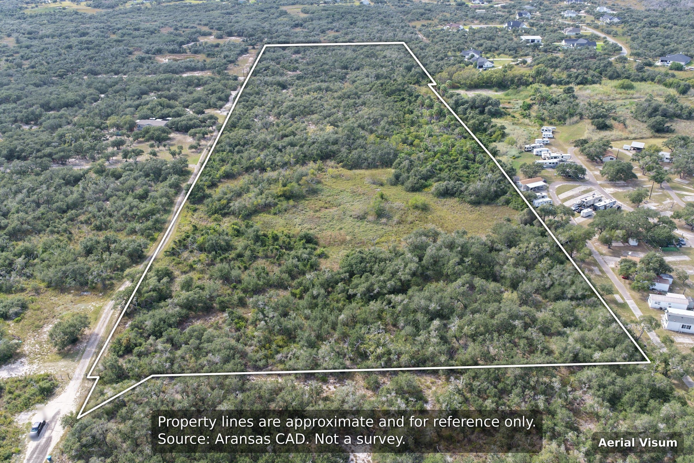 Aerial view of large wooded property outlined in white, surrounded by trees and homes.
