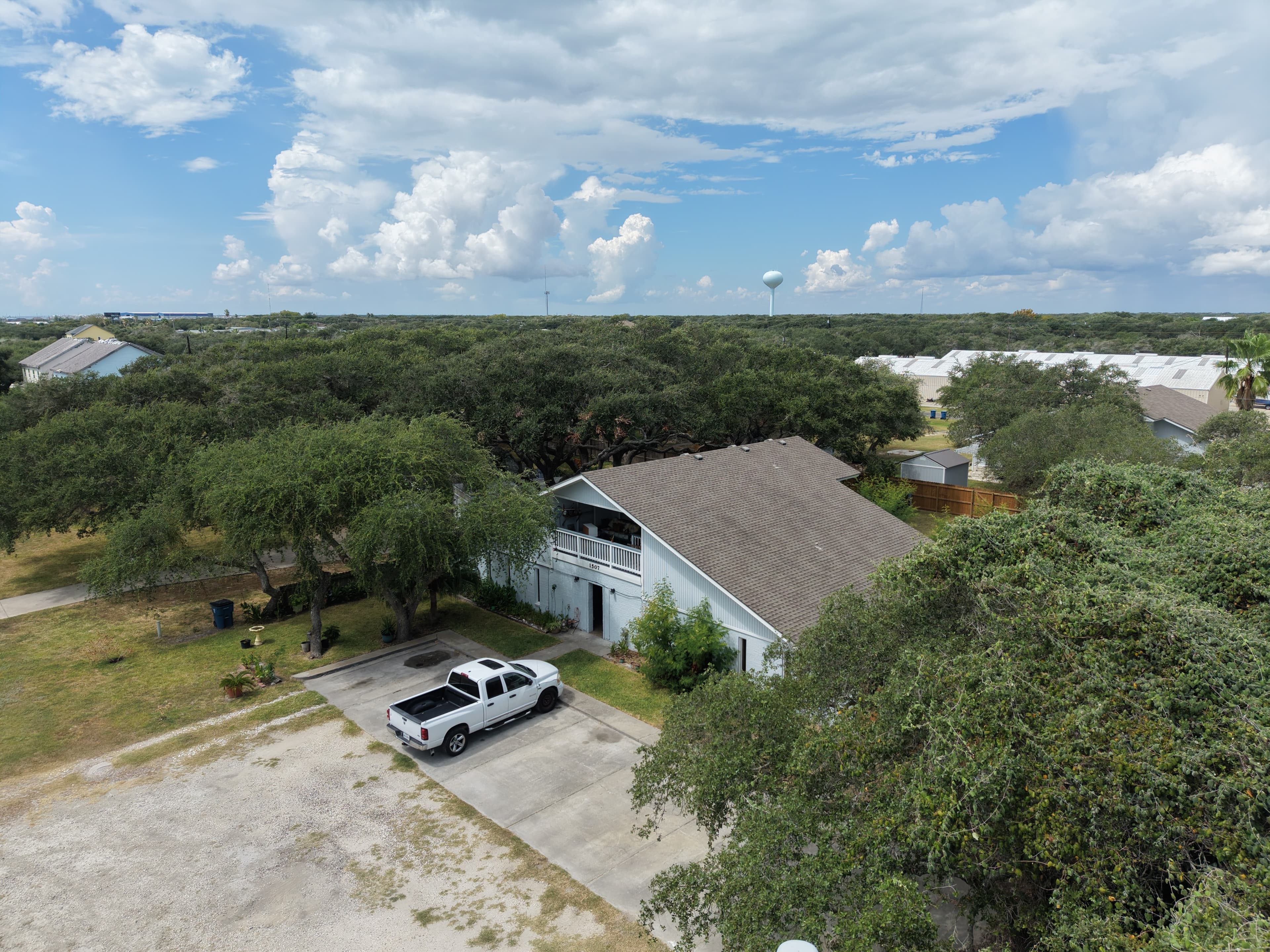 Aerial view of a blue house and white truck surrounded by lush green trees.