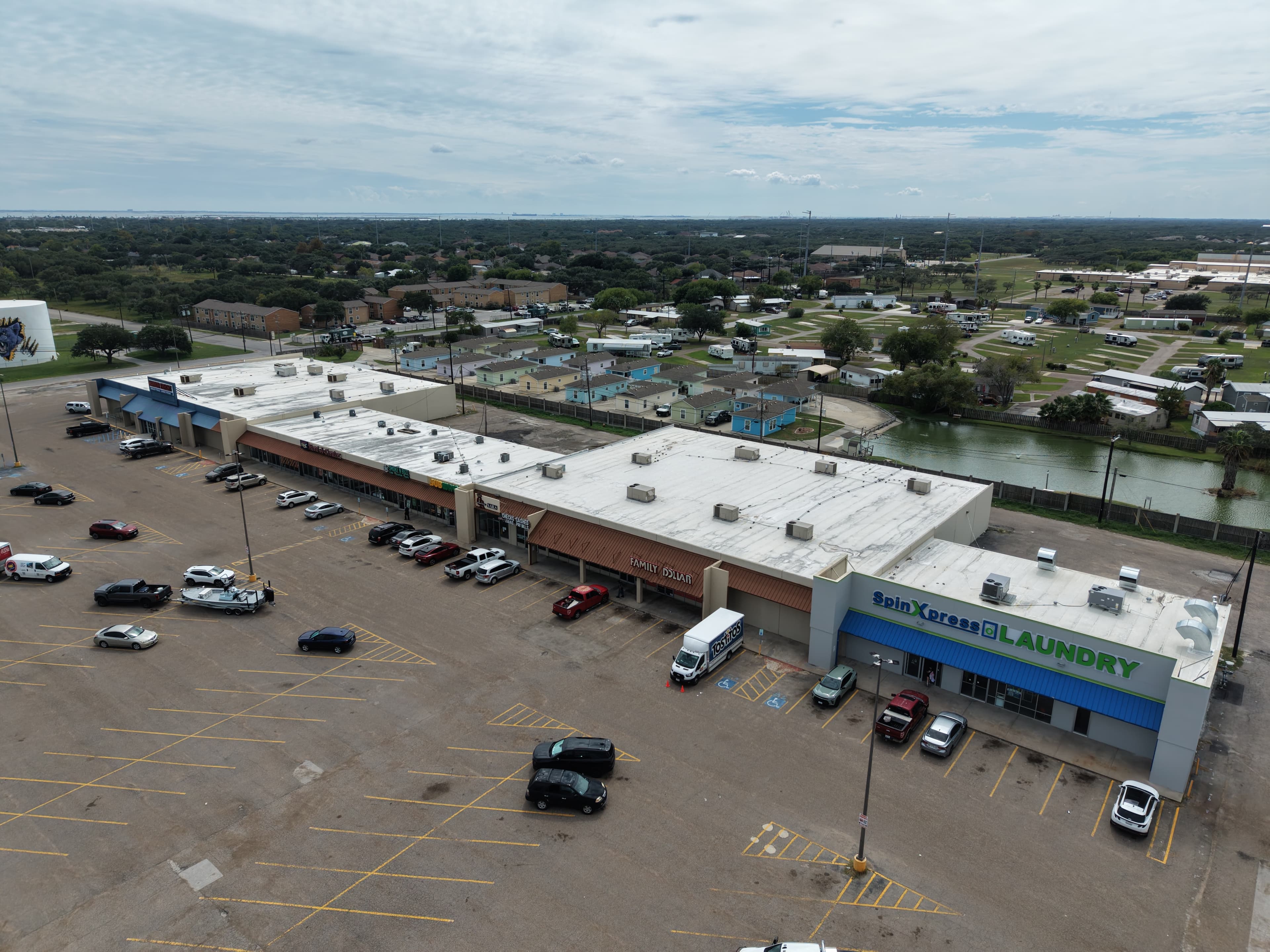 Aerial view of a strip mall featuring Family Dollar and SpinXpress Laundry with parked cars.