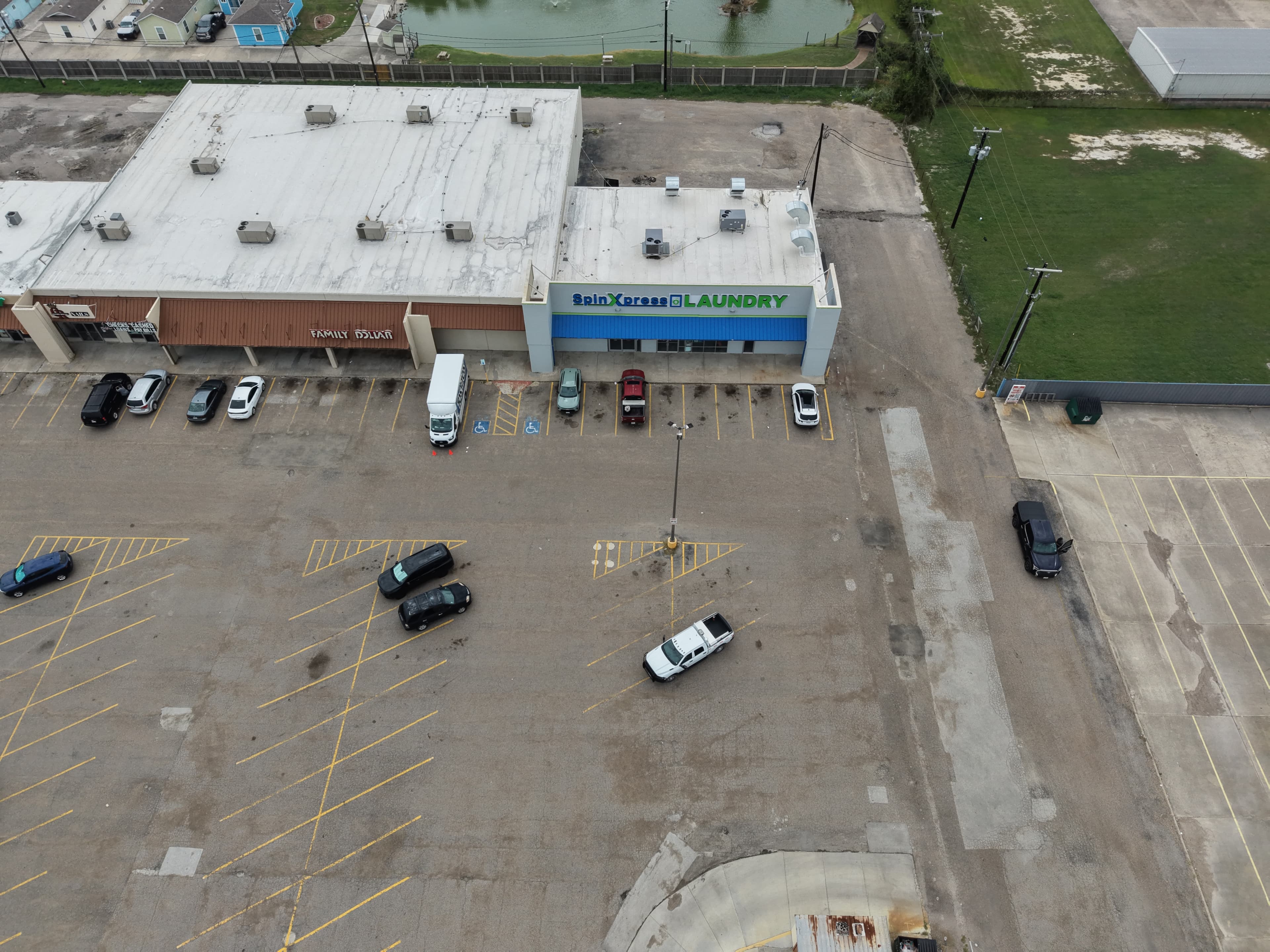 Aerial view of a shopping center featuring SpinXpress Laundry, Family Dollar, and a large parking lot.